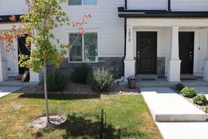 Property entrance with stone siding, a yard, and covered porch