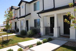 View of front of home featuring a porch, a front yard, and stone siding