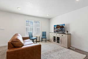 Living area with light wood finished floors, recessed lighting, and a textured ceiling