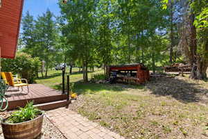View of grassy yard with a deck and view of scattered trees