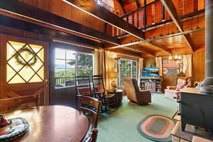 Living area with wooden walls, carpet, a wood ceiling with exposed beams, a chandelier, and cooling unit