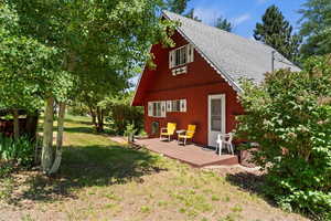 Rear view of property featuring a shingled roof, a deck, and a yard