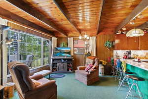 Living room with carpet floors, wooden walls, cooling unit, and a wooden ceiling with exposed beams