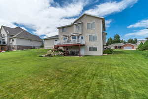 Back of house featuring a lawn, a deck, and a patio