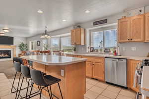 Kitchen featuring stainless steel appliances, a kitchen breakfast bar, a kitchen island, light brown cabinetry, and open floor plan
