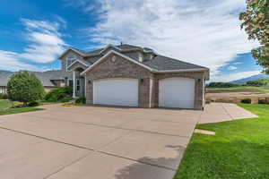 View of front facade with a garage, driveway, a front lawn, and brick siding