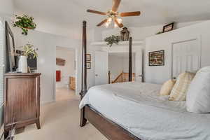 Bedroom with light colored carpet, lofted ceiling, connected bathroom, and ceiling fan