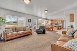 Living area with light colored carpet, a chandelier, and recessed lighting