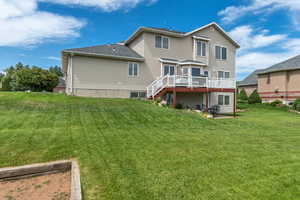 Back of house featuring a wooden deck, a yard, and stairs