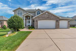 Traditional-style house featuring concrete driveway, an attached garage, a front yard, brick siding, and stucco siding
