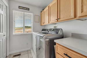 Laundry area featuring cabinet space, washing machine and clothes dryer, and light tile patterned floors