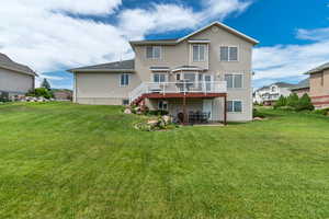 Rear view of house featuring a deck, a patio, a yard, and stairs