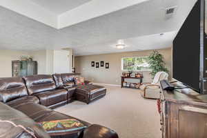 Carpeted living area featuring a textured ceiling and baseboards