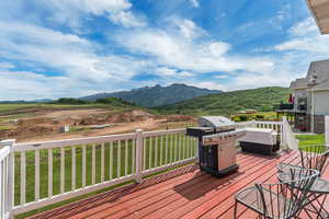Deck with a grill, a mountain view, and a yard