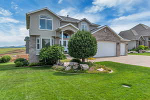 View of front of property featuring a garage, brick siding, a front lawn, and driveway