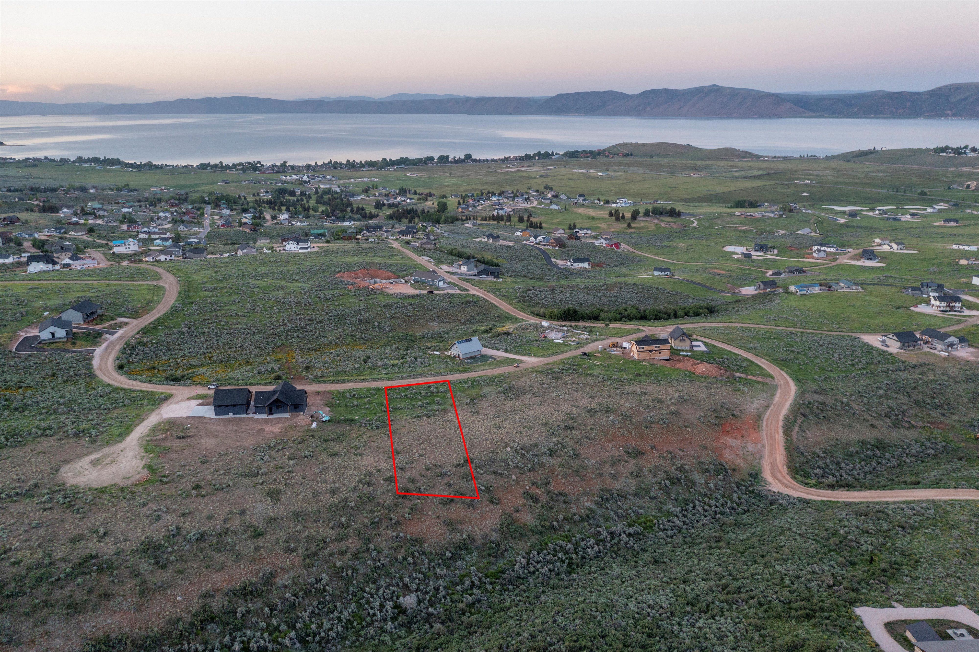 Aerial view at dusk of a water and mountain view and property boundaries highlighted