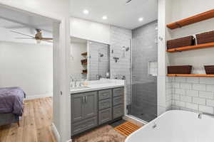 Bathroom with a stall shower, vanity, a soaking tub, ceiling fan, and wood finished floors