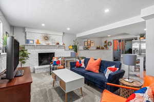 Carpeted living area with a textured ceiling, recessed lighting, and a fireplace