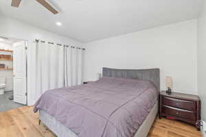 Bedroom with wood finished floors, ensuite bath, recessed lighting, vaulted ceiling, and ceiling fan