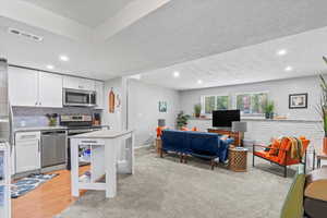 Kitchen with stainless steel appliances, white cabinets, recessed lighting, a textured ceiling, and tasteful backsplash