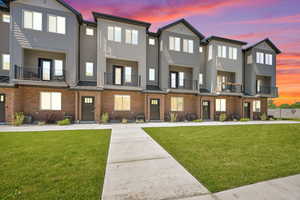 Townhome / multi-family property with a front lawn, brick siding, a standing seam roof, and board and batten siding