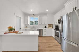 Kitchen with stainless steel appliances, white cabinets, light wood finished floors, light countertops, and recessed lighting
