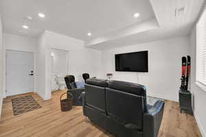 Cinema room with light wood-style floors and recessed lighting