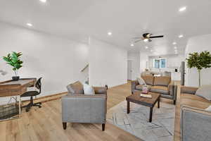 Living area with light wood-type flooring, recessed lighting, ceiling fan, and stairs