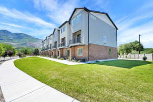 View of home's exterior featuring a lawn, brick siding, and a mountain view