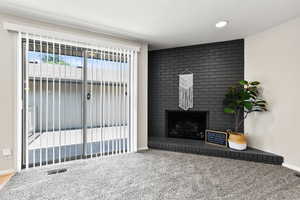 Carpeted living room featuring a fireplace and a textured ceiling