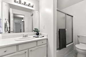Bathroom featuring vanity and bath / shower combo with glass door