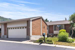 View of front of house featuring a garage, brick siding, and a mountain view
