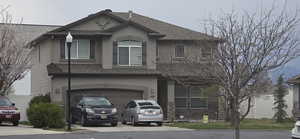 View of front of home with stucco siding, driveway, a garage, and roof with shingles