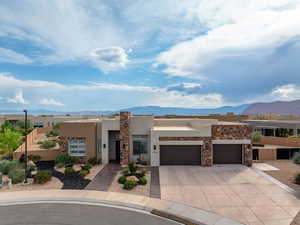 Pueblo-style house featuring a mountain view, stucco siding, concrete driveway, and an attached garage