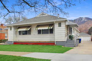 Bungalow-style home with a mountain view, an outbuilding, a front yard, a detached garage, and a shingled roof