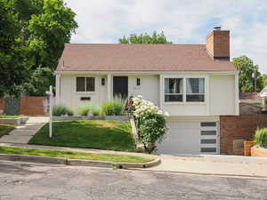 View of front of home featuring a chimney, a garage, and driveway