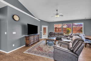Living area featuring ceiling fan, wood finished floors, and lofted ceiling