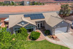 View of front of home with a tiled roof, an attached garage, a mountain view, roof mounted solar panels, and concrete driveway