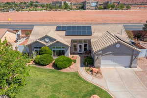 View of front facade featuring a tiled roof, a garage, roof mounted solar panels, driveway, and stucco siding