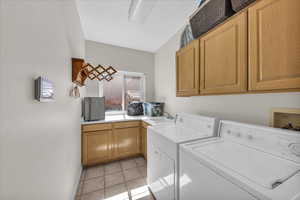 Laundry area featuring cabinet space, washer and clothes dryer, and light tile patterned floors