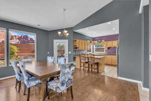 Dining area with a chandelier, light wood-style flooring, healthy amount of natural light, lofted ceiling, and recessed lighting