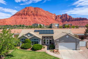 View of front of property with a tile roof, solar panels, a garage, and a mountain view