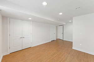 Finished below grade area with light wood-style flooring and recessed lighting