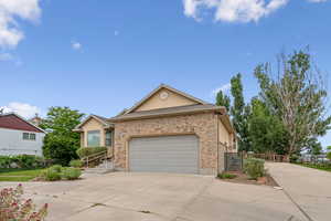 Single story home featuring driveway, an attached garage, brick siding, and stucco siding