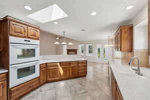 Kitchen with double oven, a skylight, light countertops, a peninsula, and recessed lighting