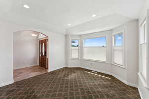 Carpeted empty room featuring arched walkways and recessed lighting