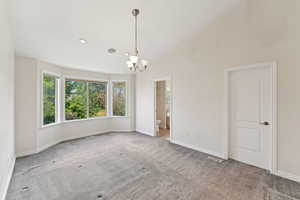 Empty room featuring a chandelier and carpet flooring