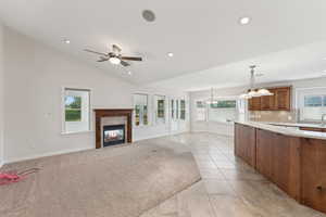 Kitchen with brown cabinets, light countertops, pendant lighting, a tile fireplace, and recessed lighting