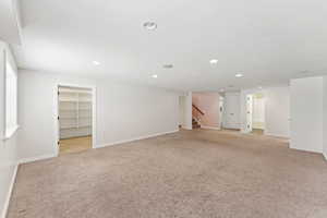 Basement featuring light colored carpet, recessed lighting, and stairs