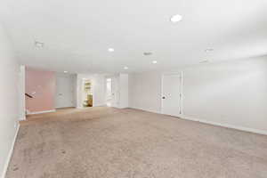 Unfurnished room featuring recessed lighting, light colored carpet, and stairway